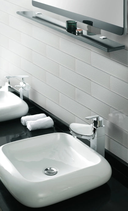 Modern bathroom with white square sink, chrome faucet, and glass backsplash tiles, reflecting a minimalist luxurious design.
