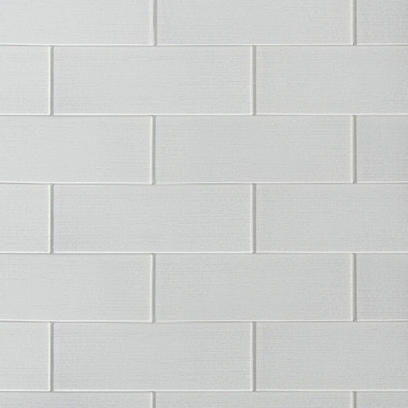 Linen ice 4-in x 12-in glass wall tiles with reflective surface, ideal for modern kitchen backsplashes and bathroom walls.