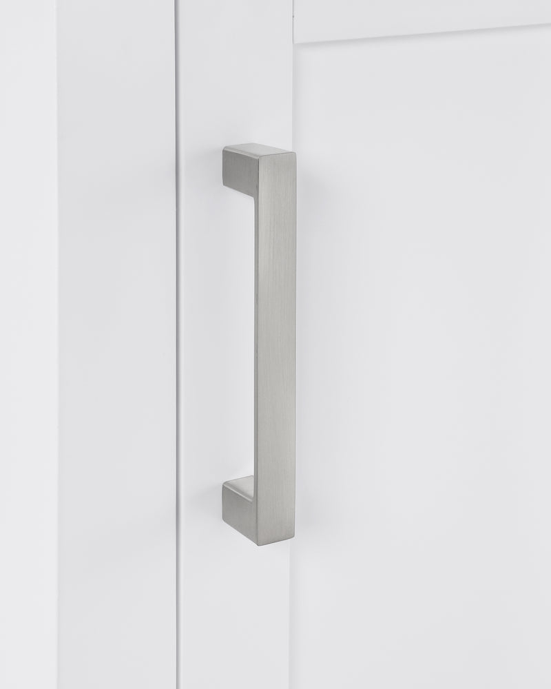 Close-up of a sleek brushed nickel cabinet handle on a white cabinet door.