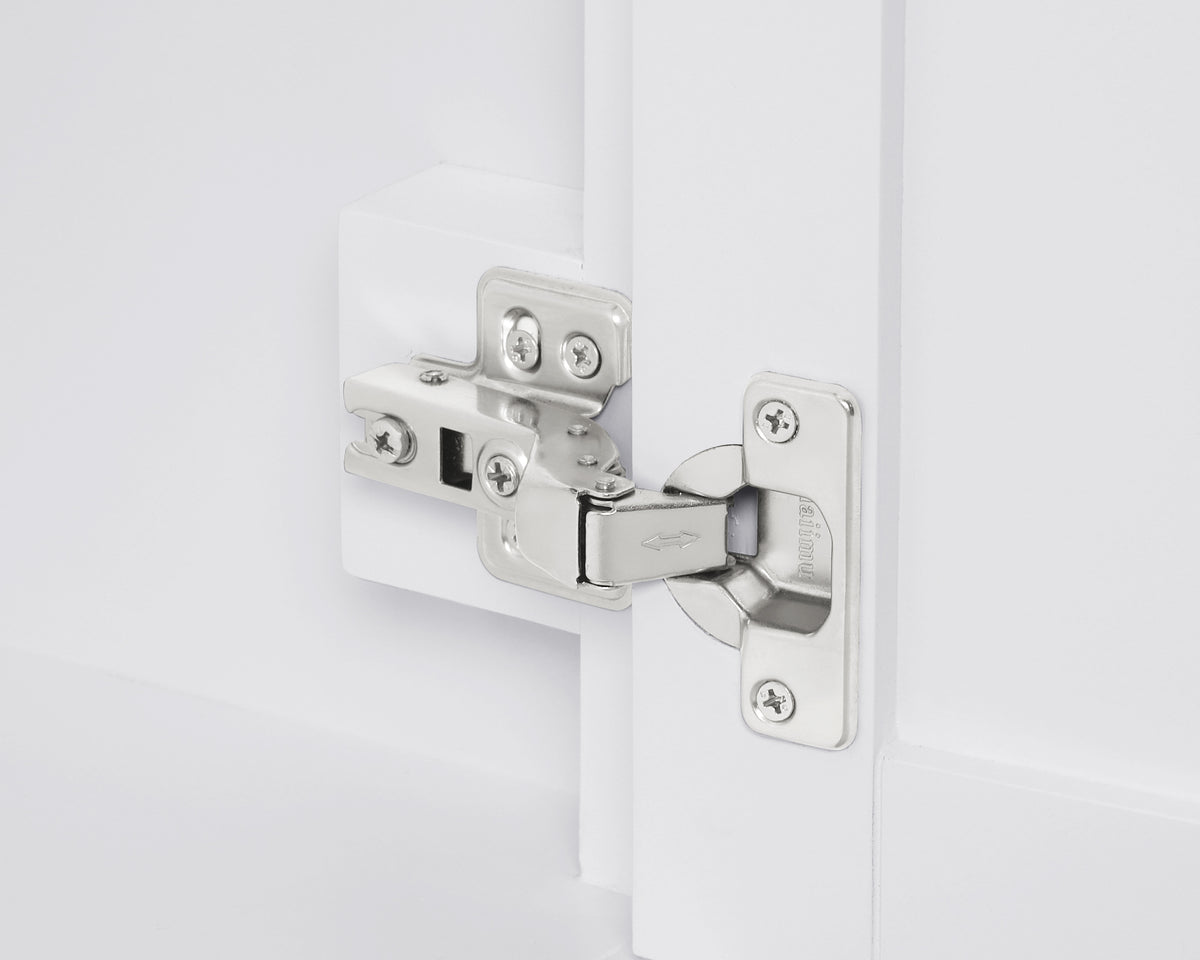 Close-up of a hinge on a white cabinet door, showcasing sleek metal design for modern interiors.